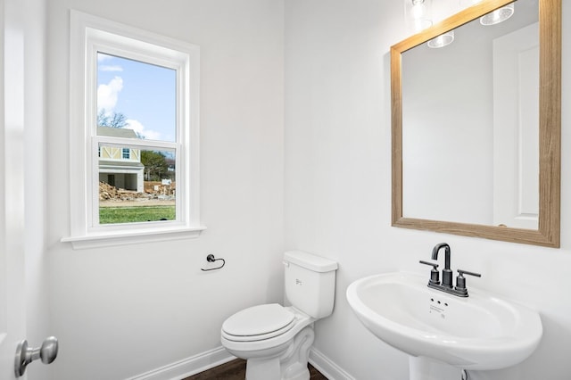 bathroom with a sink, toilet, and baseboards