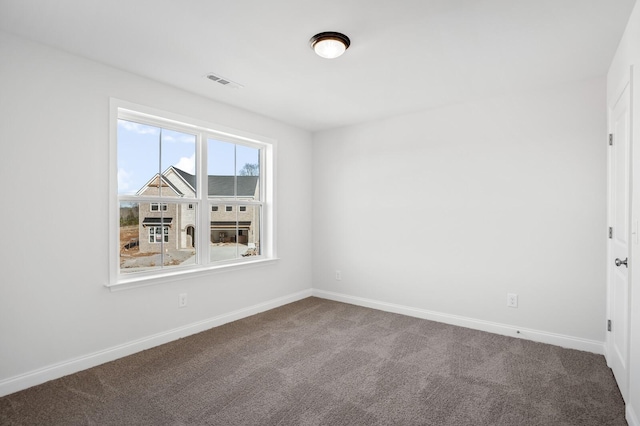 unfurnished room with baseboards, visible vents, and dark carpet