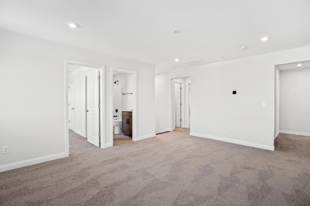 unfurnished bedroom featuring light carpet, ensuite bath, baseboards, and recessed lighting