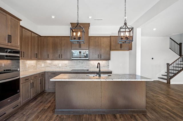 kitchen with decorative backsplash, dark wood-style floors, appliances with stainless steel finishes, light stone counters, and a sink