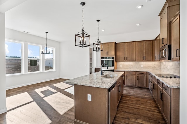 kitchen featuring light stone counters, dark wood finished floors, stainless steel appliances, decorative backsplash, and a sink