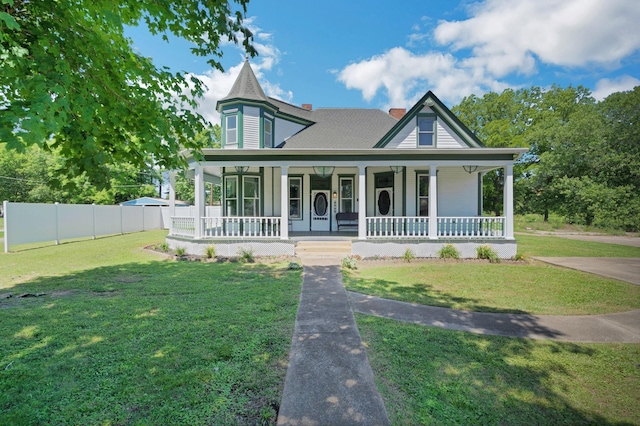 victorian home with covered porch, a chimney, fence, and a front yard