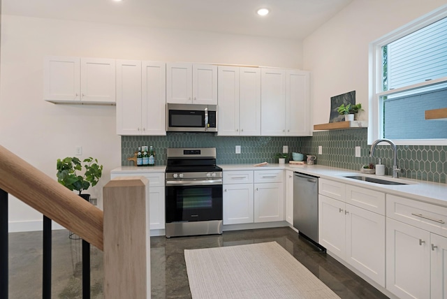 kitchen featuring open shelves, appliances with stainless steel finishes, a sink, and decorative backsplash