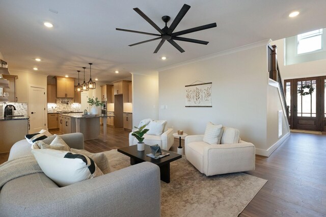 living room with recessed lighting, baseboards, dark wood-style floors, crown molding, and ceiling fan with notable chandelier