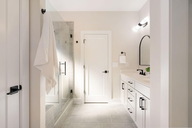 full bathroom featuring double vanity, a stall shower, a sink, and tile patterned floors