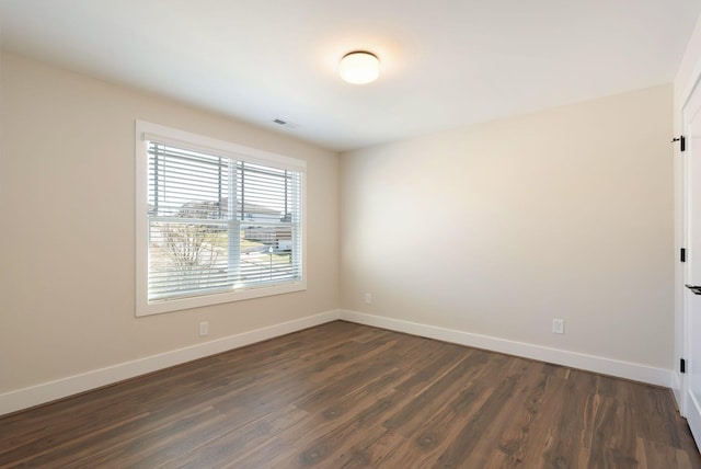 unfurnished room featuring dark wood-style floors, visible vents, and baseboards