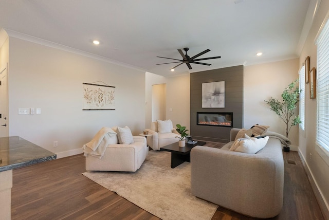 living room with a large fireplace, ornamental molding, dark wood-style flooring, and a healthy amount of sunlight