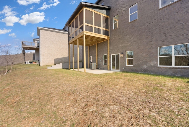 back of property with brick siding, a yard, a sunroom, a patio area, and cooling unit