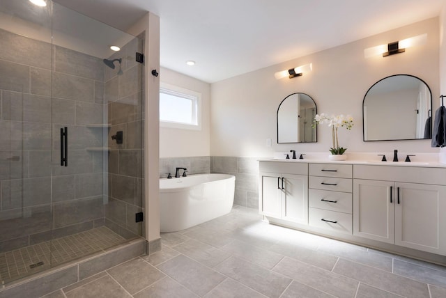 bathroom with double vanity, a stall shower, a soaking tub, and a sink