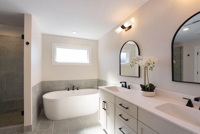 bathroom featuring a freestanding tub, a stall shower, and a sink