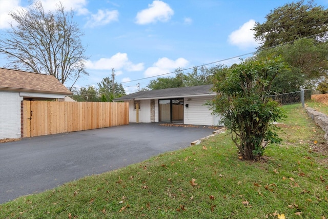 view of front of property with driveway, fence, and a front yard