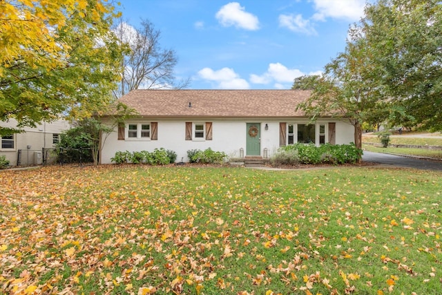 ranch-style home with stucco siding, fence, and a front yard