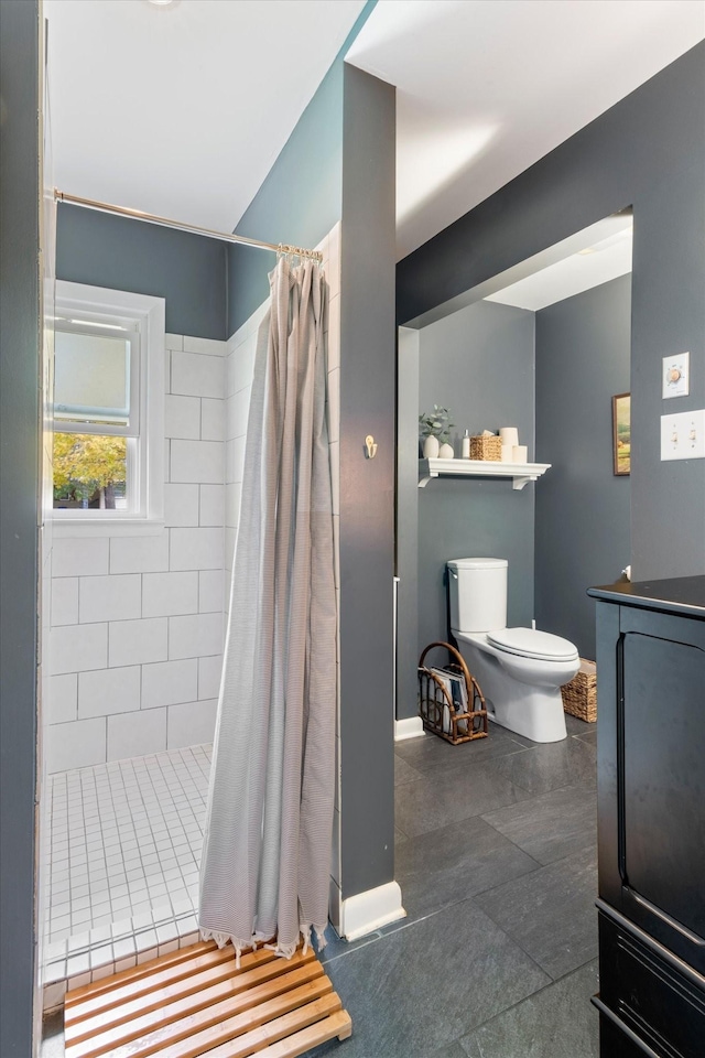 bathroom with baseboards, tiled shower, and toilet