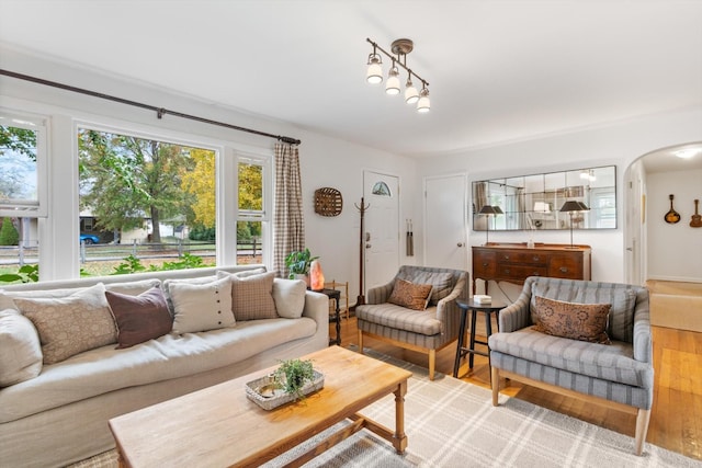 living area featuring arched walkways and light wood finished floors