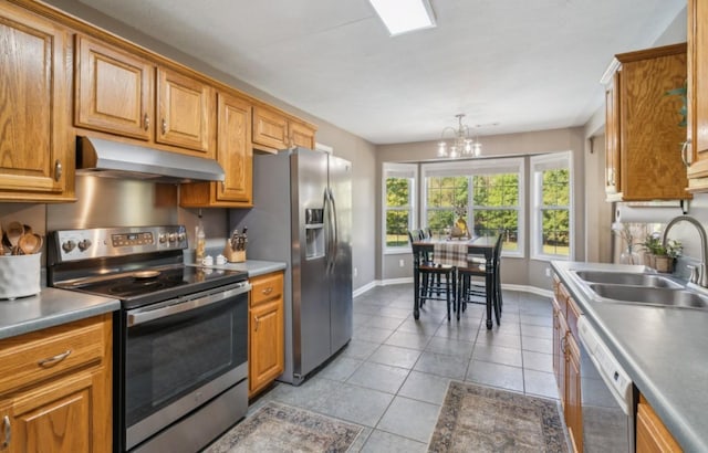 kitchen featuring a notable chandelier, under cabinet range hood, a sink, appliances with stainless steel finishes, and light tile patterned floors