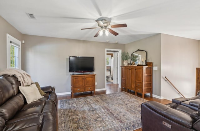 living room featuring baseboards, wood finished floors, visible vents, and ceiling fan