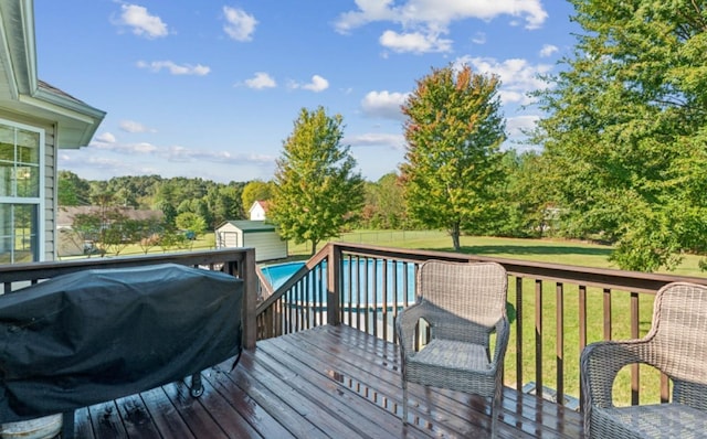 wooden deck with an outbuilding, a fenced in pool, a yard, a storage unit, and a grill