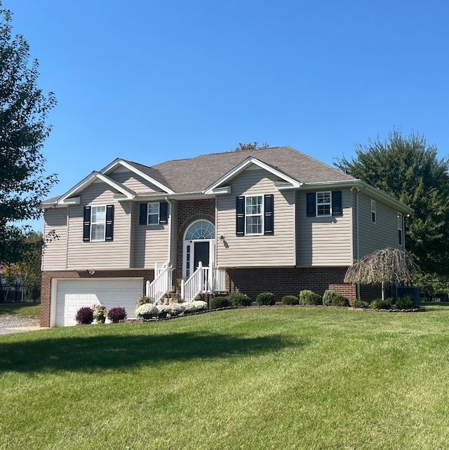 split foyer home with a front yard, brick siding, an attached garage, and roof with shingles