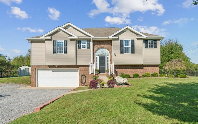 bi-level home with an attached garage, brick siding, gravel driveway, and a front yard