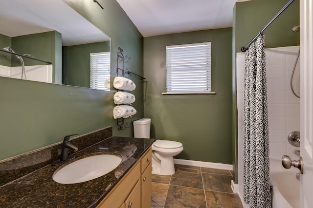 bathroom featuring a wealth of natural light, vanity, toilet, and baseboards