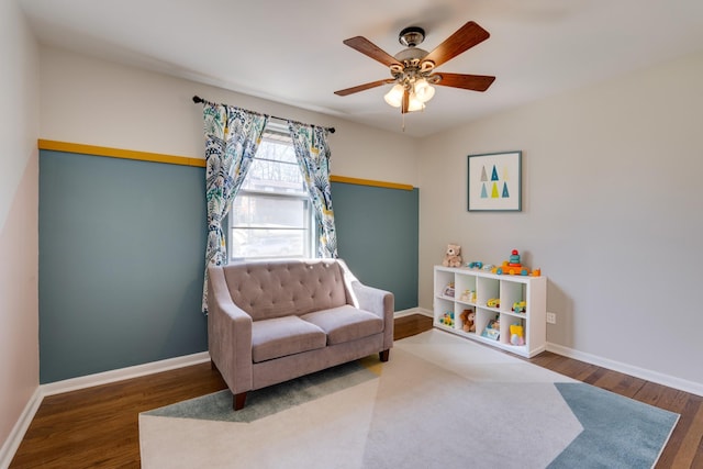 sitting room featuring a ceiling fan, baseboards, and wood finished floors