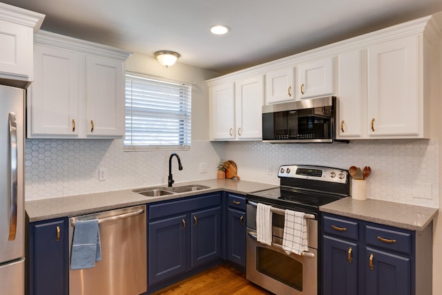 kitchen with appliances with stainless steel finishes, a sink, and blue cabinetry