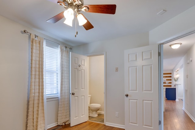 bedroom featuring light wood finished floors, connected bathroom, a ceiling fan, and baseboards