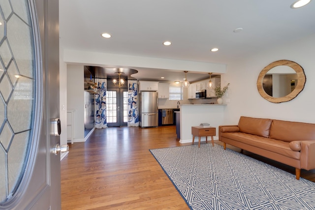 living room featuring recessed lighting, french doors, light wood-style flooring, and baseboards