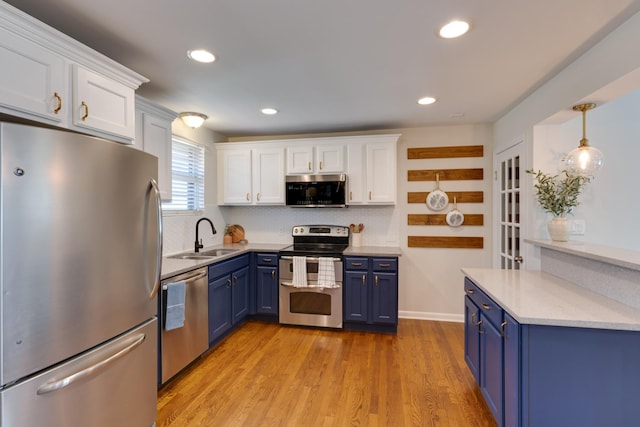 kitchen featuring blue cabinetry, light wood-style flooring, appliances with stainless steel finishes, white cabinetry, and a sink