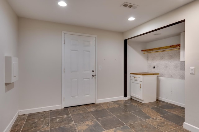 clothes washing area with recessed lighting, stone finish flooring, visible vents, and baseboards