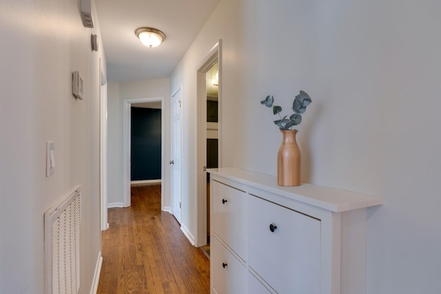 hall with visible vents, light wood-style flooring, and baseboards