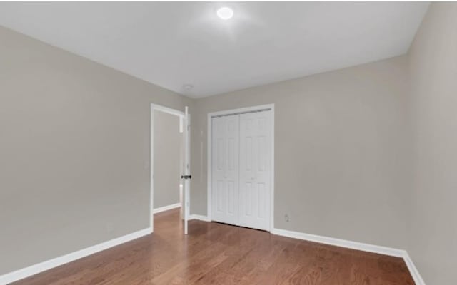 unfurnished bedroom featuring a closet, baseboards, and wood finished floors