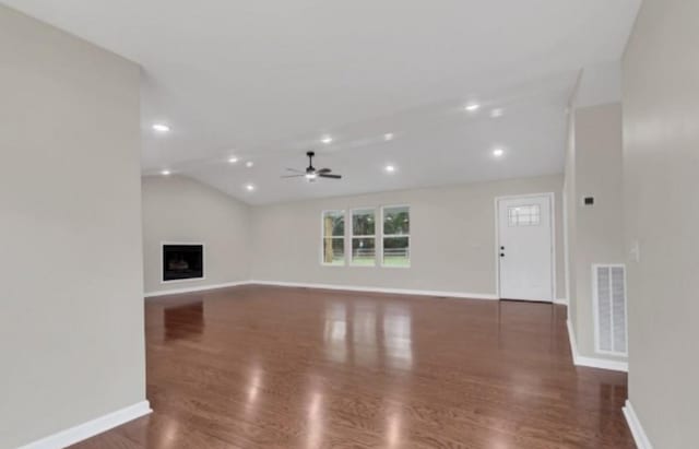 unfurnished living room with lofted ceiling, visible vents, a fireplace, and wood finished floors