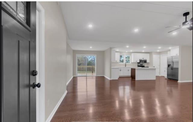 unfurnished living room with a ceiling fan, recessed lighting, dark wood finished floors, and baseboards