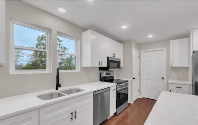 kitchen featuring recessed lighting, stainless steel appliances, a sink, white cabinets, and light countertops