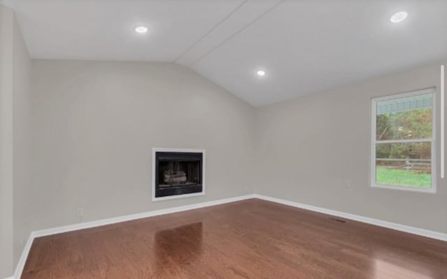 interior space featuring vaulted ceiling, a fireplace, dark wood finished floors, and baseboards