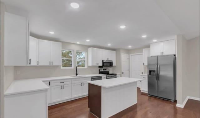 kitchen featuring dark wood-style floors, a center island, appliances with stainless steel finishes, white cabinetry, and a sink