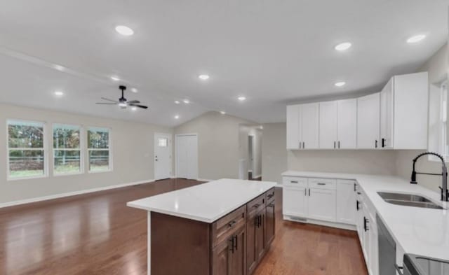 kitchen with light countertops, stainless steel dishwasher, dark wood-type flooring, a sink, and range