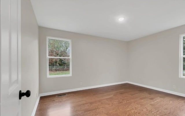 spare room featuring visible vents, baseboards, and wood finished floors