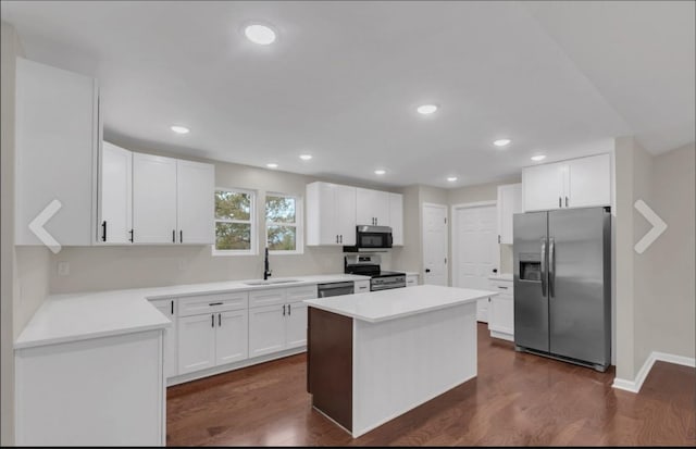 kitchen featuring appliances with stainless steel finishes, a sink, dark wood-style floors, and a kitchen island