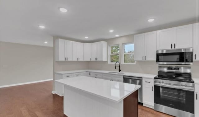 kitchen featuring a kitchen island, a sink, white cabinetry, light countertops, and appliances with stainless steel finishes