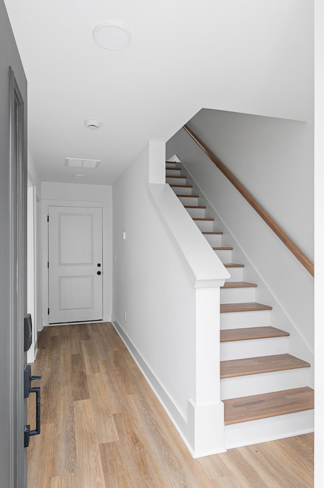 interior space featuring baseboards, visible vents, stairway, and wood finished floors