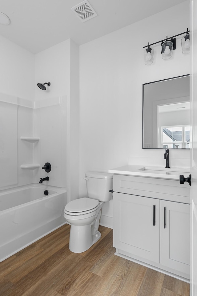 bathroom with toilet, washtub / shower combination, wood finished floors, and visible vents