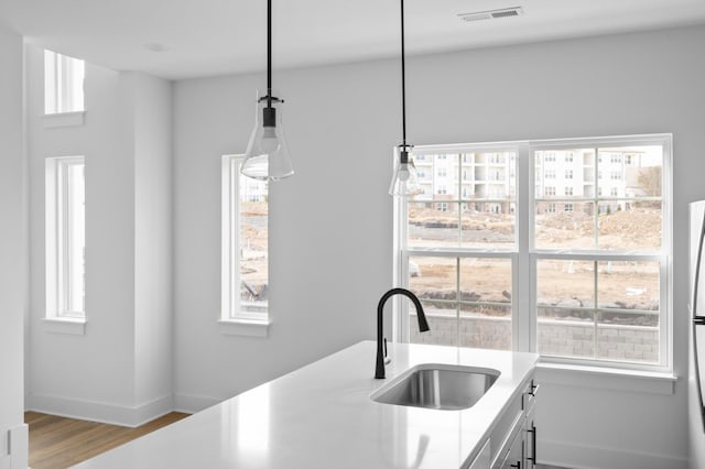 kitchen featuring light countertops, a healthy amount of sunlight, visible vents, and a sink