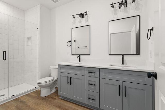 full bathroom featuring a sink, a shower stall, toilet, and wood finished floors