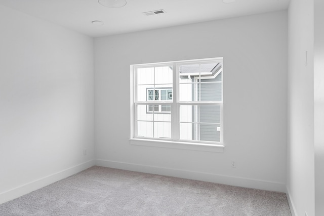 spare room featuring carpet flooring, visible vents, and baseboards