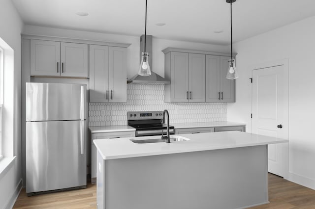 kitchen featuring a sink, light countertops, appliances with stainless steel finishes, gray cabinets, and wall chimney exhaust hood