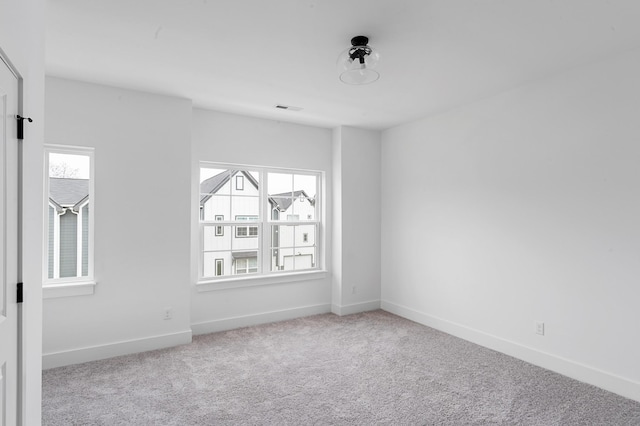 empty room featuring carpet flooring, visible vents, and baseboards