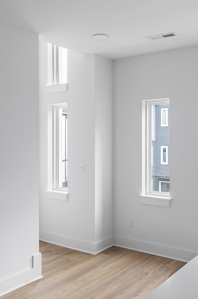 spare room featuring baseboards, visible vents, and light wood finished floors