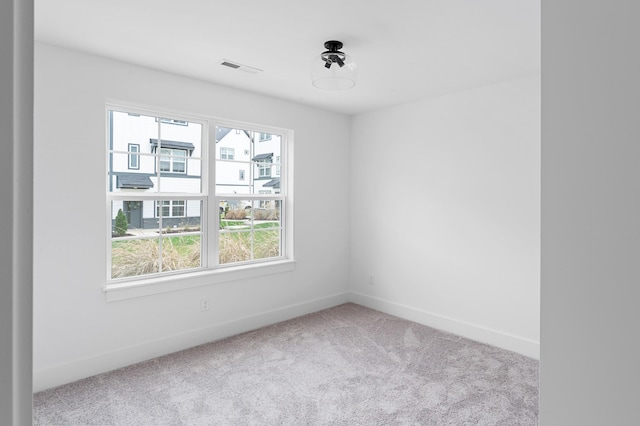 carpeted spare room featuring visible vents and baseboards